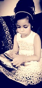 Close-up of cute girl sitting on bed at home