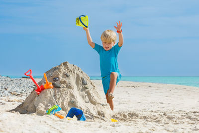 Rear view of woman with arms raised standing at beach