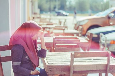 Side view of woman sitting on bench