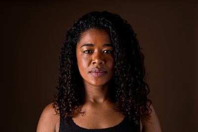 Portrait of young woman against black background