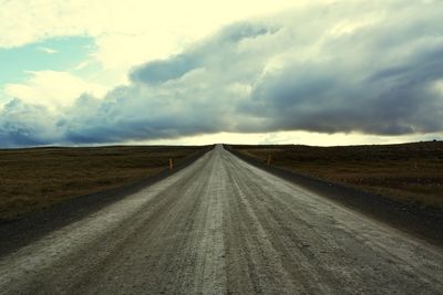 Empty road amidst land against sky