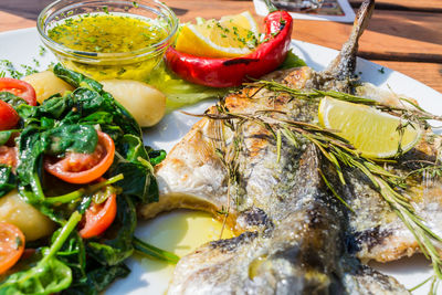 Close-up of fish with salad served in plate on table