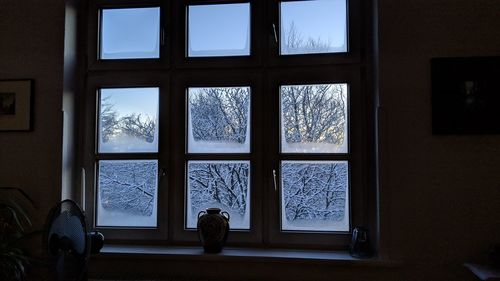 Rear view of woman looking through window in house