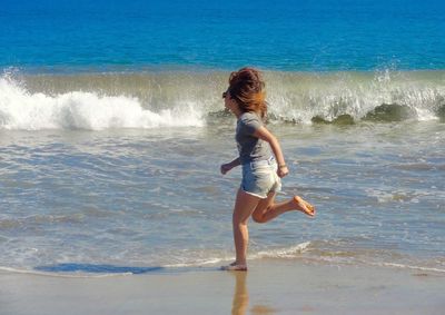 Side view of woman running at shore