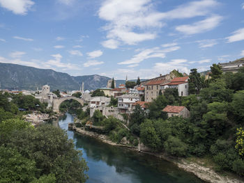 Bridge over river by buildings against sky