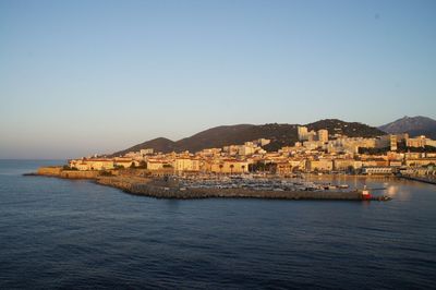 Scenic view of sea by buildings against clear sky