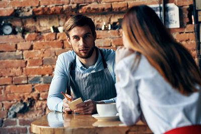 Waiter taking order of female customer at cafe