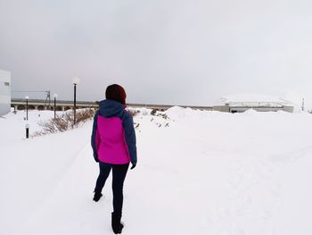 Rear view of woman standing on snow covered land against sky