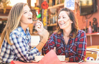 Cheerful female friends having coffee while sitting at table in cafe
