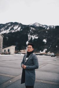 Full length portrait of young man standing on road against sky