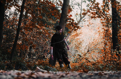 Person standing by tree in forest during autumn