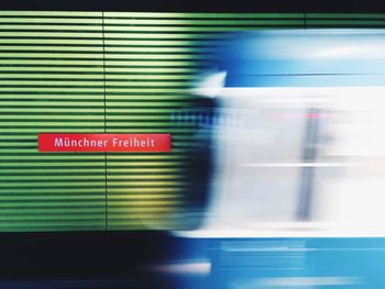 Blurred motion of train with text on wall at subway station