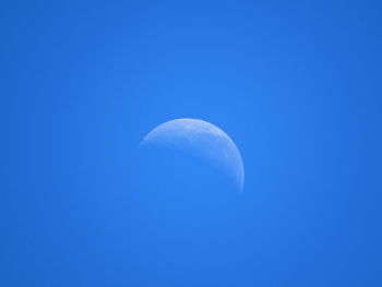 Low angle view of moon against clear blue sky