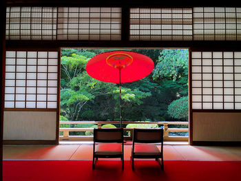 Red chairs and table against window of building