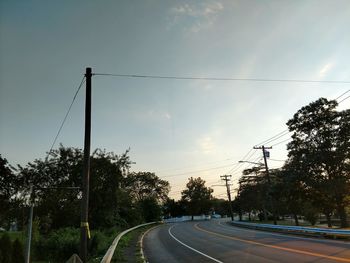 Road by trees against sky