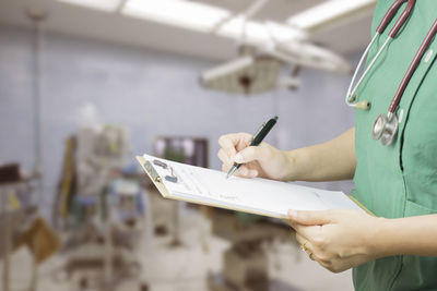 Midsection of nurse writing on paper at hospital