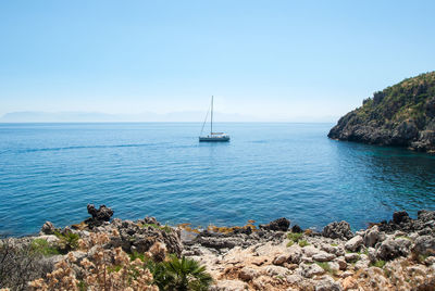 Sailboat sailing in sea against clear blue sky