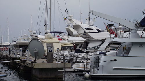 Boats moored at harbor against sky