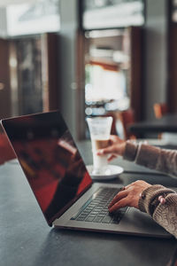 Woman working remotely on her laptop computer managing her work sitting at the table in a cafe