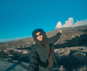 Portrait of man standing on mountain against sky