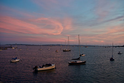 Sailboats moored on in new england harbor against a backdrop of a rose quartz sky during sunset. 