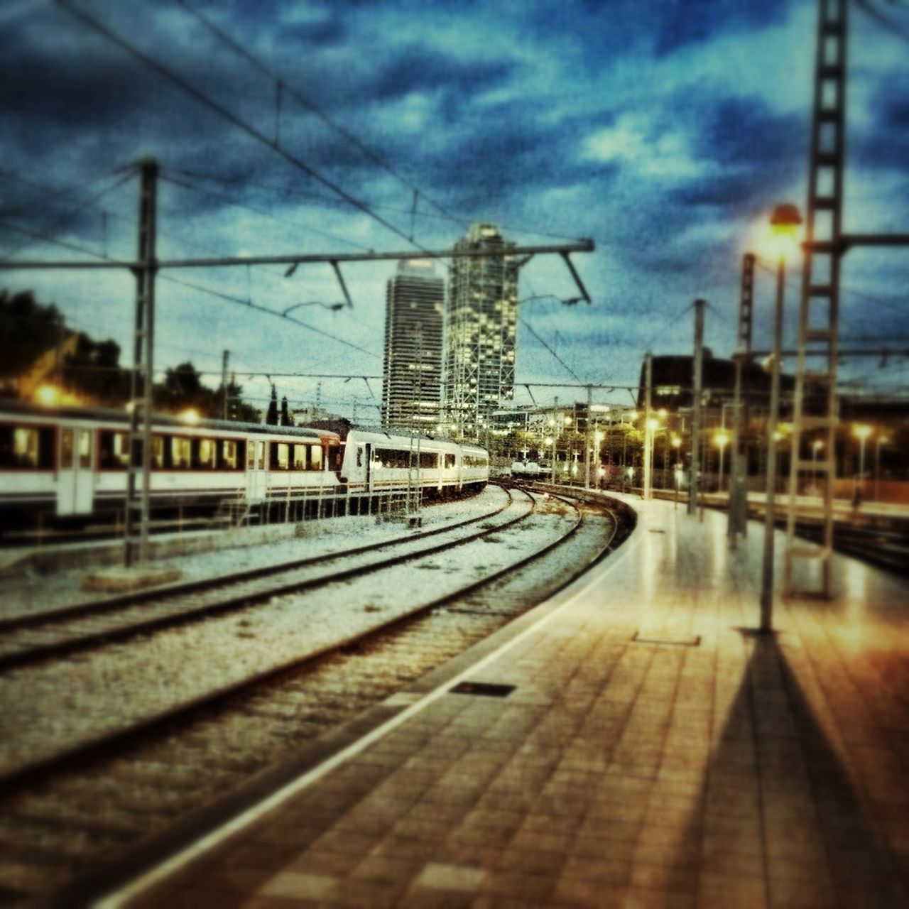 railroad track, sky, rail transportation, building exterior, cloud - sky, built structure, architecture, transportation, public transportation, railroad station, railroad station platform, cloudy, city, dusk, the way forward, cloud, weather, electricity, power line, electricity pylon