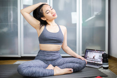 Full length of young woman sitting at home