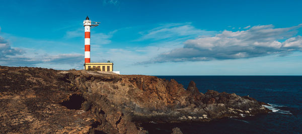 Lighthouse by sea against sky