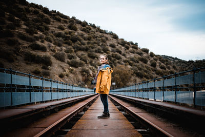 Portrait of man standing on railroad track against sky