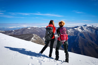 Full length of woman standing on snowcapped mountain against sky