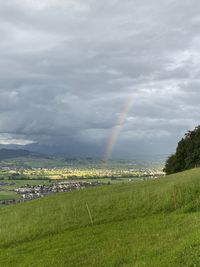 Scenic view of rainbow over field against sky