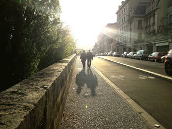 Rear view of woman walking on road along buildings