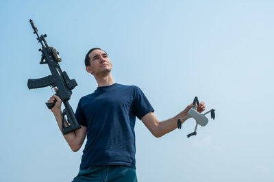 Low angle view of young man exercising against clear sky