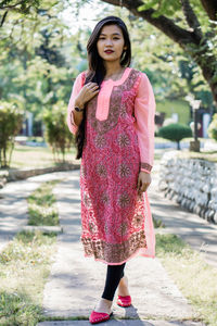 Full length of woman standing against pink umbrella