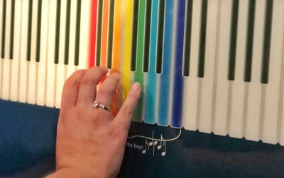 Close-up of person hand on multi colored piano
