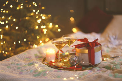 Close-up of wine glass on table against illuminated christmas lights