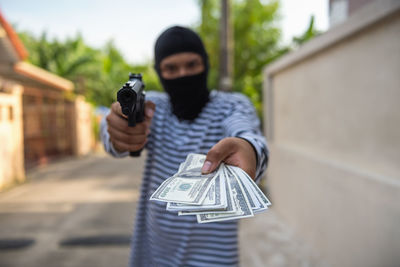 Thief holding paper currency and handgun