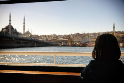 Rear view of woman looking at cityscape against sky