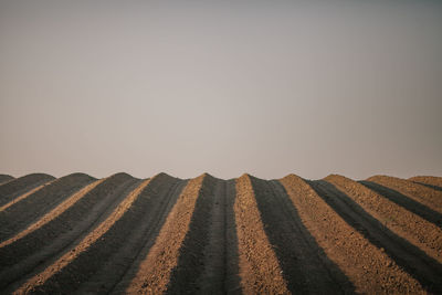 Surface level of tire track on sand against clear sky