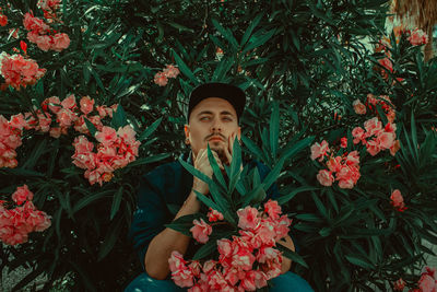 Portrait of young man amidst flowering plants