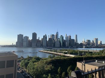 Modern buildings by river against clear sky