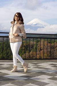 Portrait of woman standing on railing against mountain