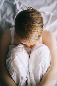 High angle view of woman sitting on bed at home