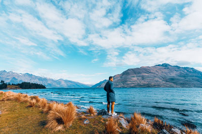 Rear view of man looking at mountains against sky