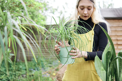 Beautiful young woman standing against plants