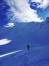 People skiing on snow covered mountain against sky