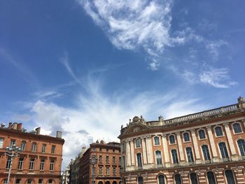 Low angle view of buildings against cloudy sky