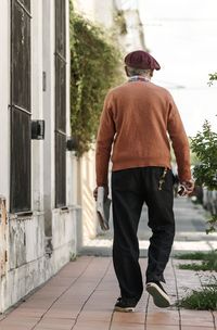 Rear view of man walking on footpath by street