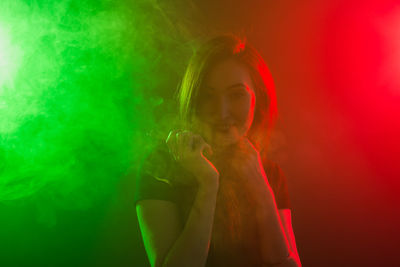 Portrait of woman against illuminated red background