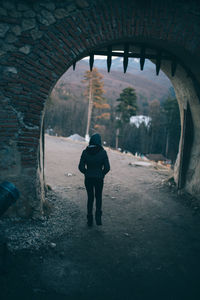 Rear view of man and woman walking in tunnel